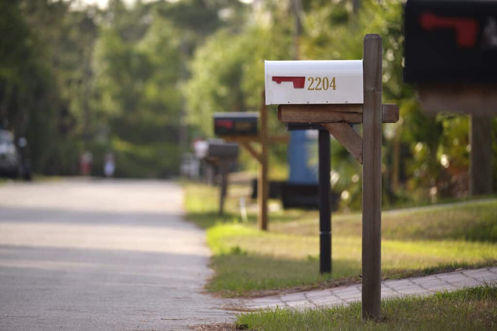 A rural-style home mailbox along a suburban street to illustrate shipping fraud by address manipulation