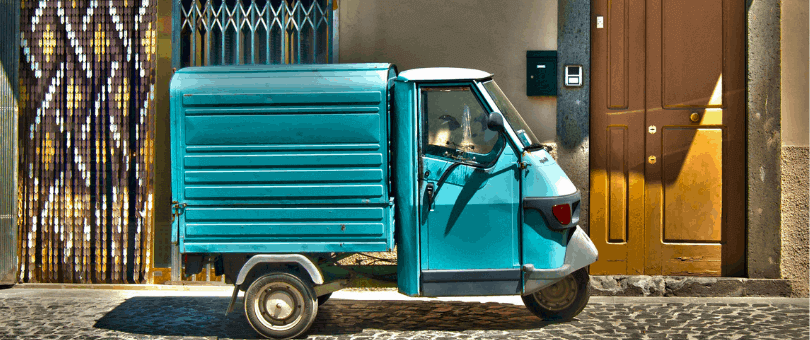 A colorful, small delivery van in front of a door